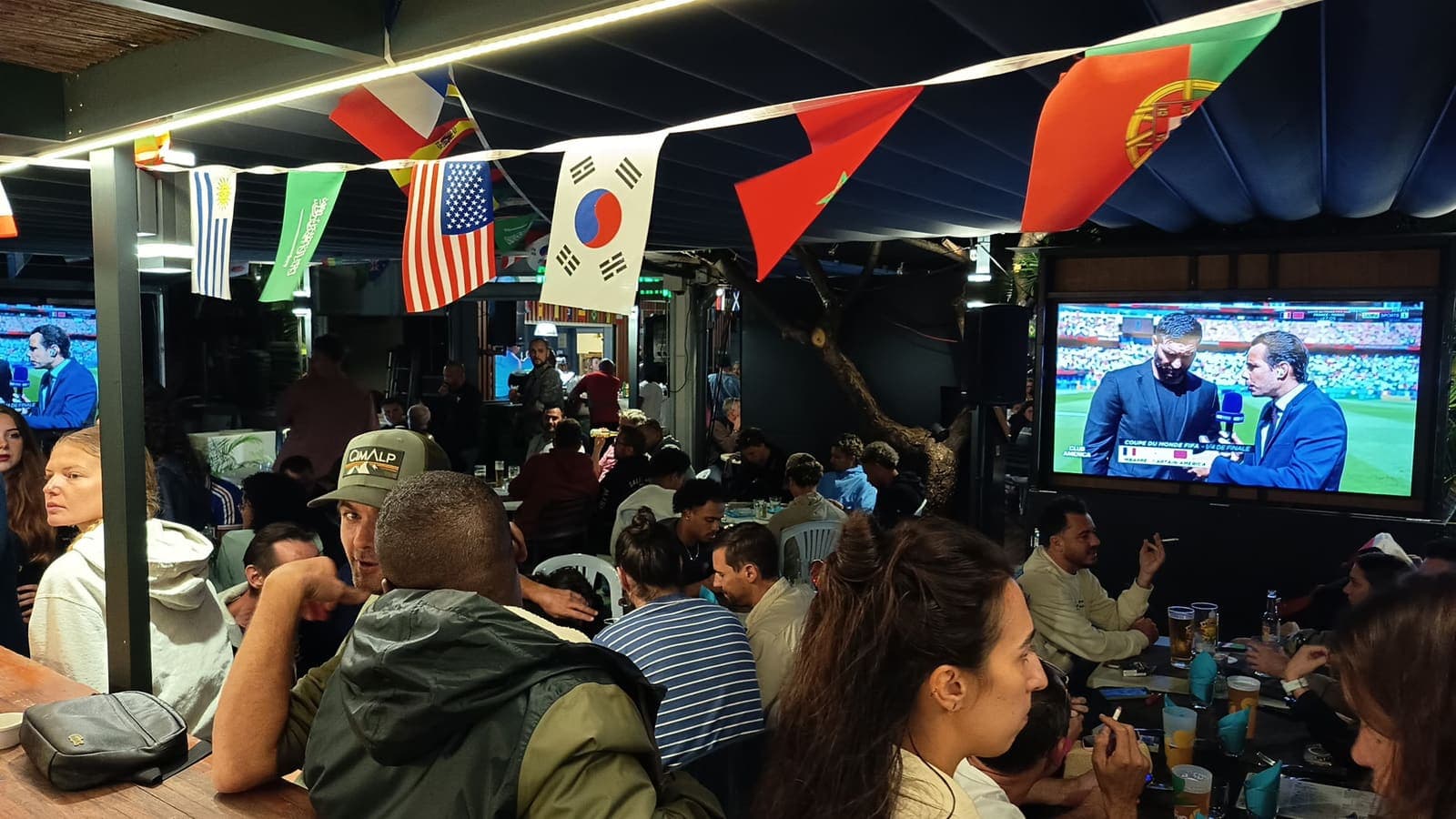 La terrasse comble un soir de match, fanions aux couleurs du monde et écrans géants