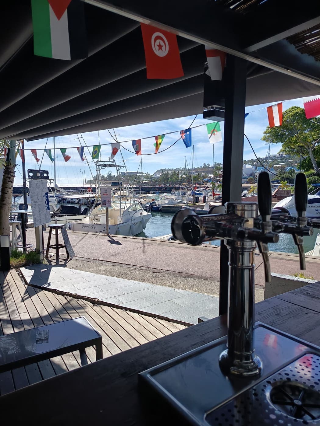 La vue depuis le comptoir du bar : les tireuses à bière face au port de plaisance de Saint-Gilles et ses bateaux